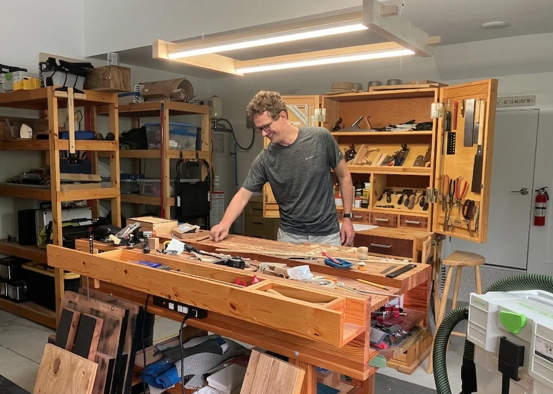Artist behind his beloved workbench in his fully equipped workshop, surrounded by tools and wood, embodying the heart of his craft.